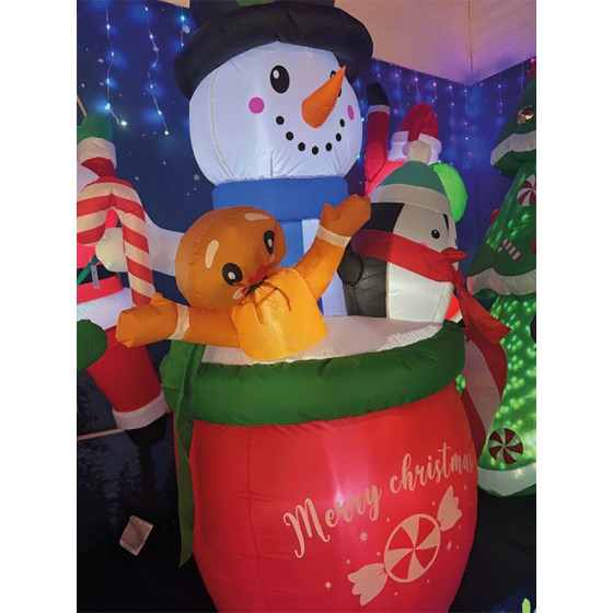 Boneco de neve insuflável num copo com um pinguim e um biscoito de gengibre